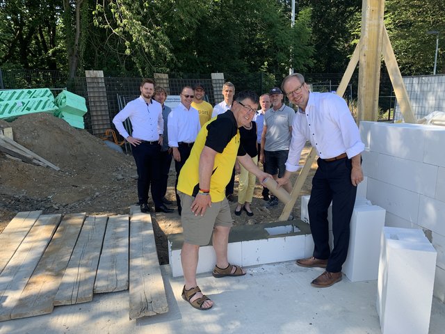 Burkhard Dickmann, Vorsitzender des SC Glessen, und der Bergheimer Bürgermeister Volker Mießeler setzen den Grundstein zum neuen Vereinsheim im Glessener Waldstadion. Mit dabei ist ein Behälter mit Erinnerungsstücken.